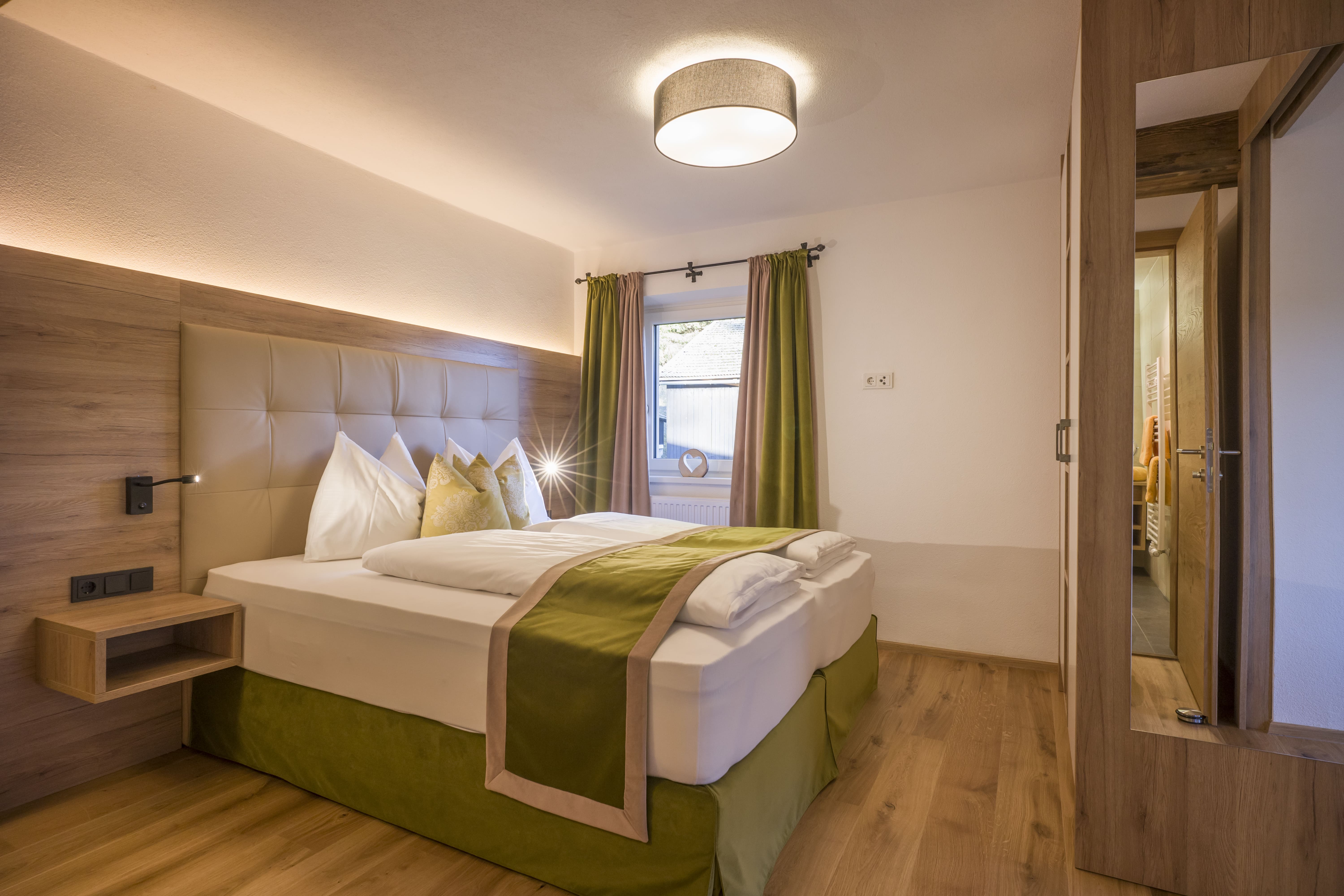 Modernes Hotelzimmer mit einem einladenden Bett und warmen Holzböden, ideal für einen entspannten Aufenthalt.